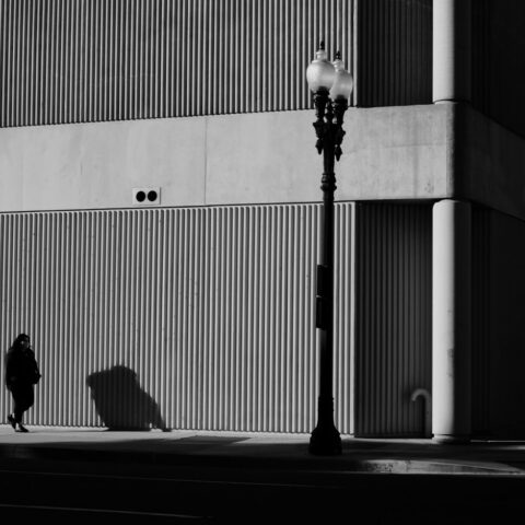 a person walking down a street next to a tall building