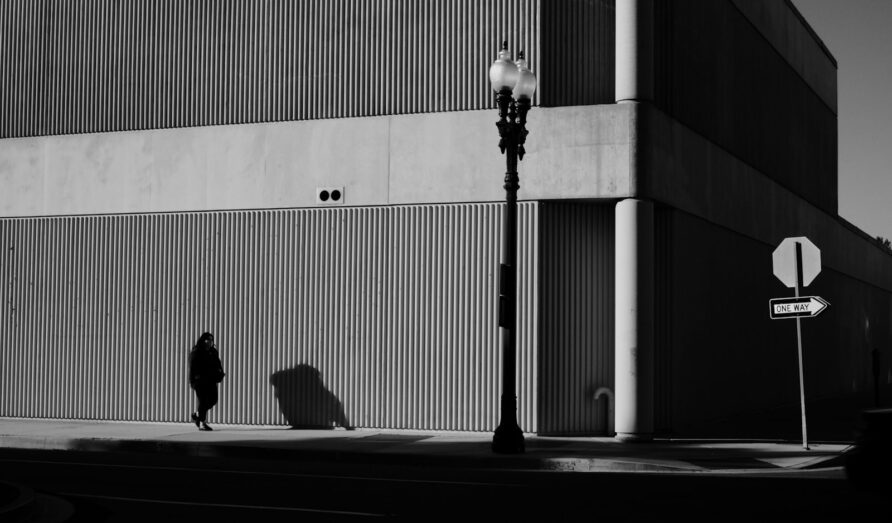 a person walking down a street next to a tall building